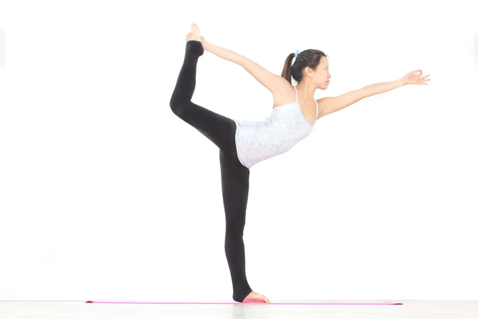 Beautiful young woman practices yoga asana Natarajasana - Lord Of The Dance  pose at the yoga studio Stock Photo by Sandsun