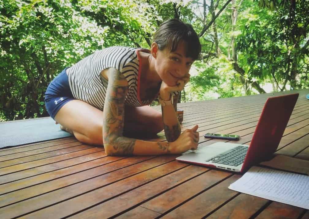 Joanne Highland at her laptop on a deck suspended in a forest