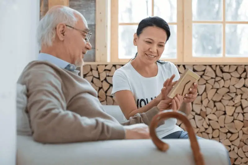 A young woman and an elderly man sit together in conversation. Giving time & listening to others is an example of karma yoga.