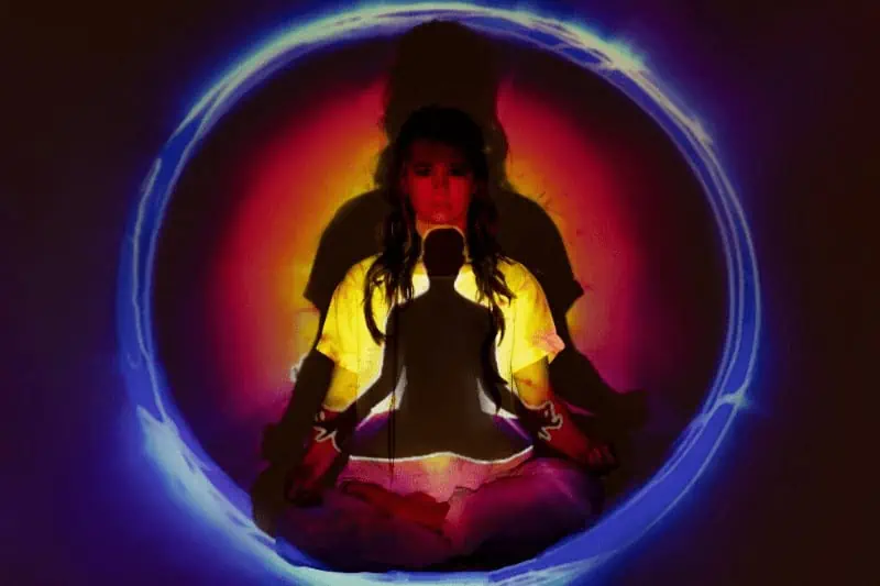 A woman meditates with projected small & large silhouettes & auras surrounding the figure as the three bodies and five koshas