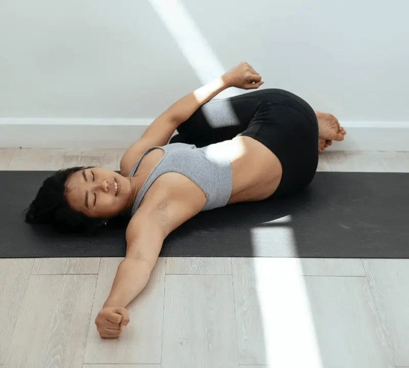 To practice spinal twist, bring your knees into your chest and let them fall to one side. Hold, then repeat on the other side.