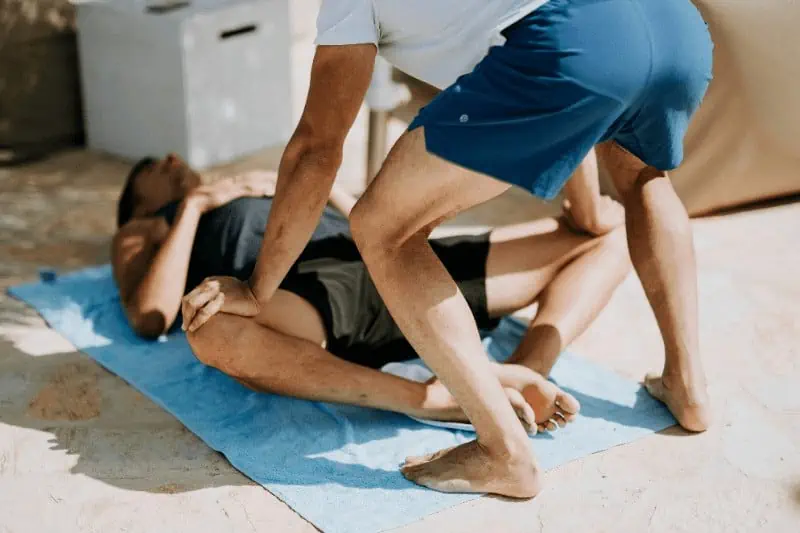 Yoga teacher giving a student an adjustment in bound angle pose